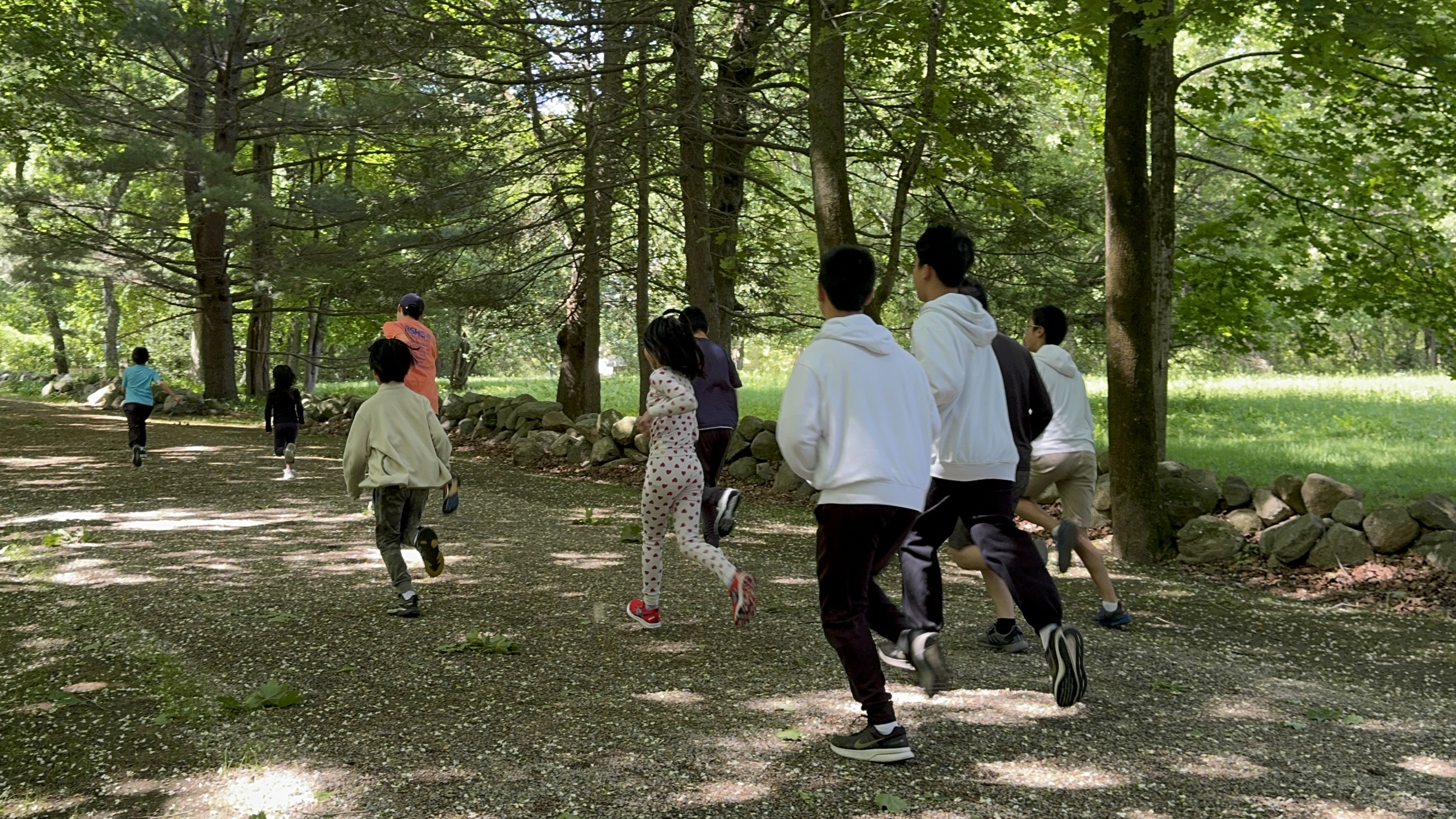 Children and volunteers running together on a wooded path